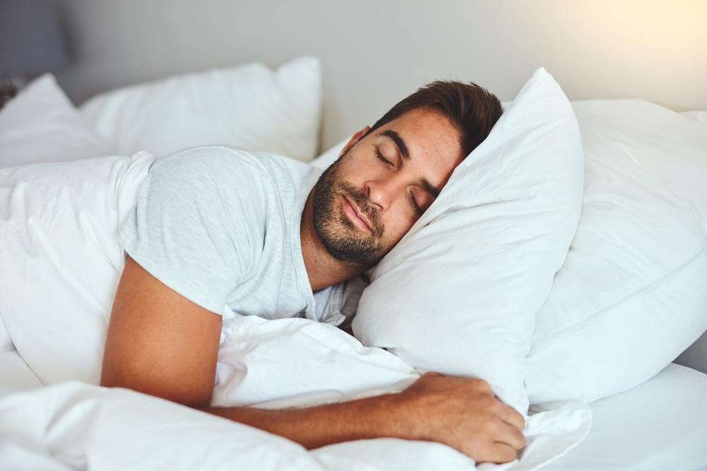 A man sleeping soundly in a hotel bed.
