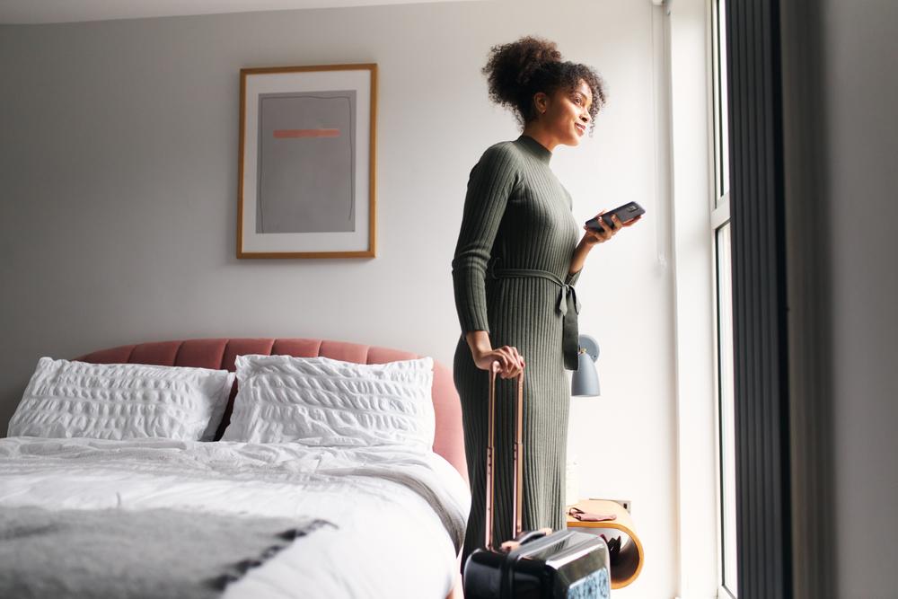 A woman standing next to the bed in a hotel room.