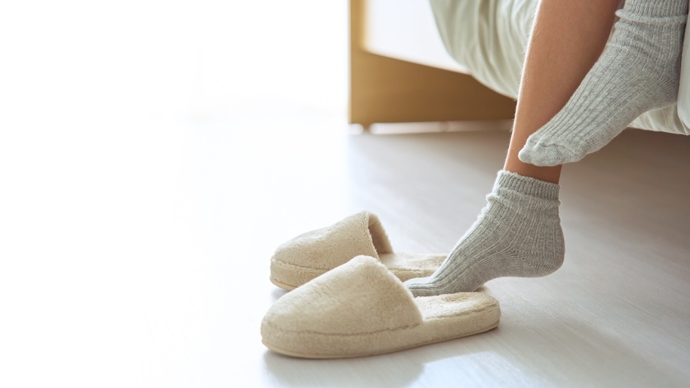 A woman’s feet stepping into custom slippers.