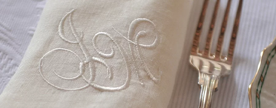 A high-quality napkin embroidered with initials in an elegant cursive script.